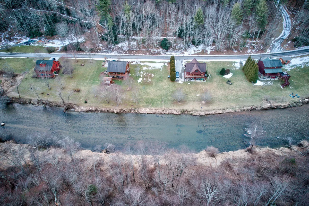 This image shows houses nestled along a riverbank, with trees and open outdoor spaces. The scene suggests a range of activities such as hiking, picnicking, and riverside play, highlighting accessibility to the outdoors.