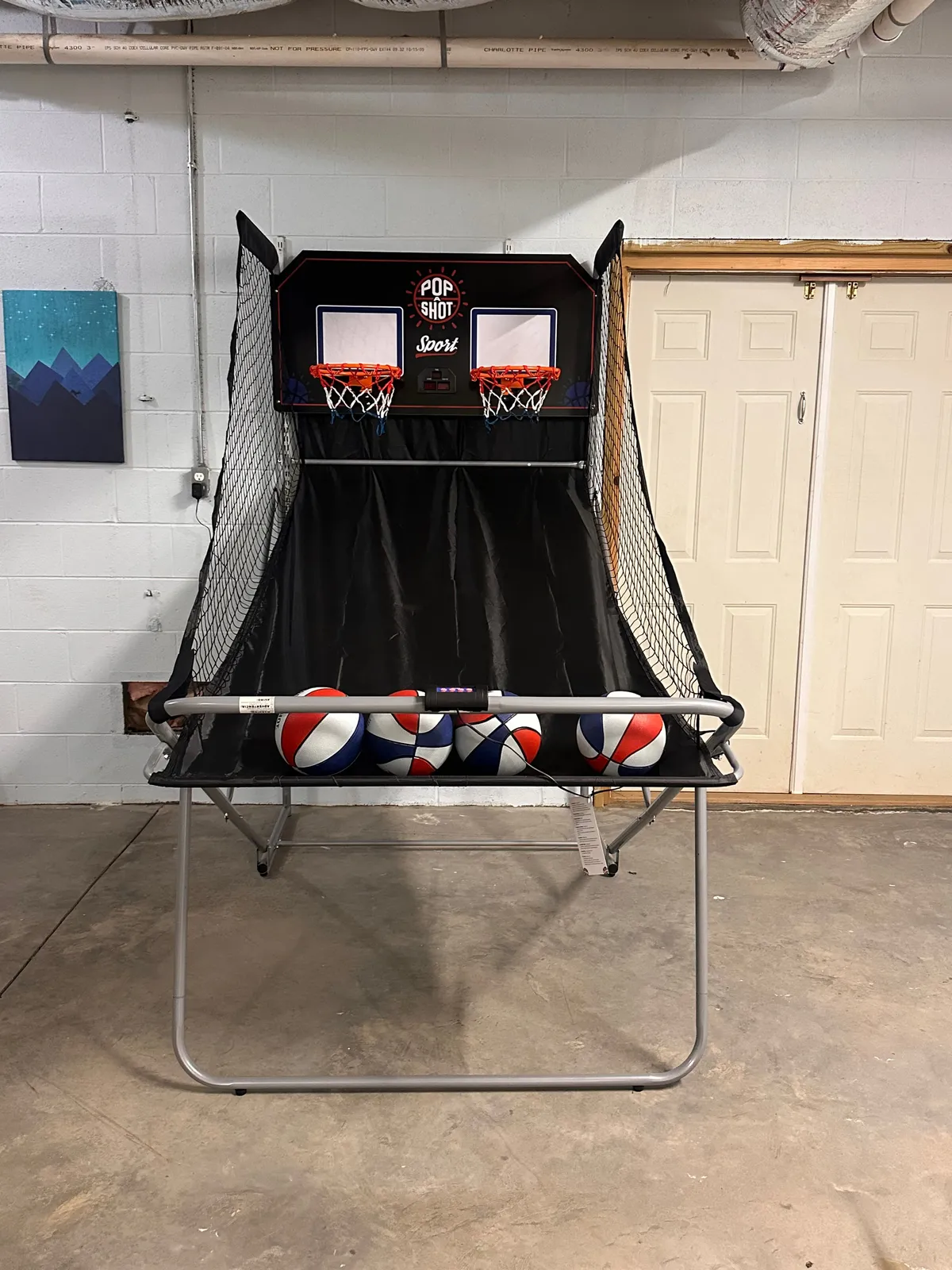 An energetic scene centered on the Pop-a-Shot basketball game, with basketballs visible and lively wall art in the background. The space radiates excitement and invites friendly competition among guests.